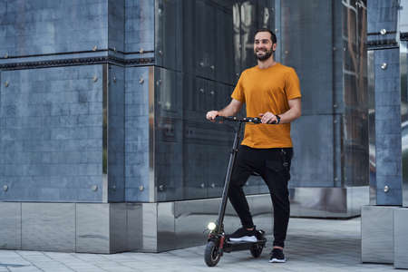 Cheerful handsome guy using eco transport in cityの写真素材