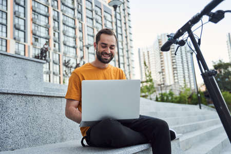 Smiling bearded man with notebook and scooter outdoorsの写真素材