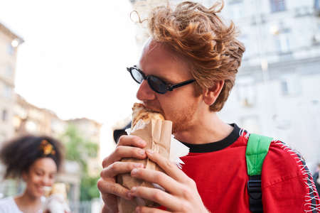 Young stylish man enjoying street meal outdoorsの写真素材