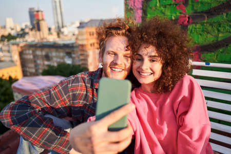Happy young couple taking selfie while dating on roof