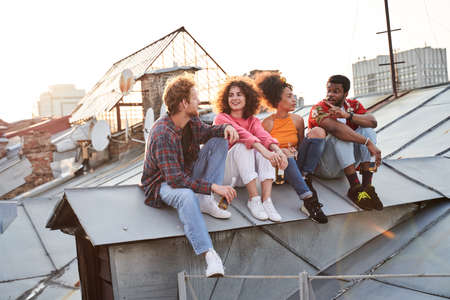 Happy friends relaxing with beer on roof