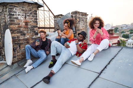 Jolly young people surfing internet together outdoors