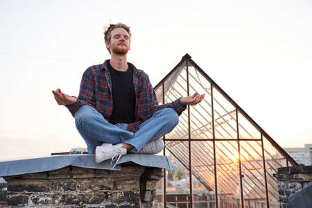 Calm handsome man doing meditation on roofの写真素材