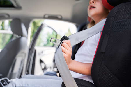 Little girl using safety belt in automobile chairの写真素材