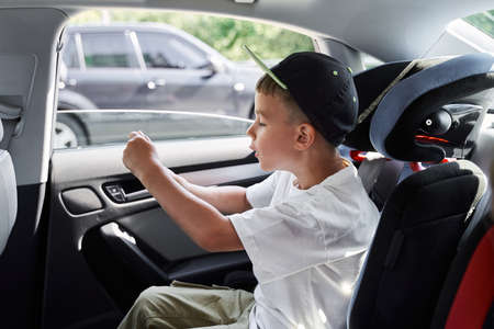 Jolly boy with smartphone going by carの写真素材