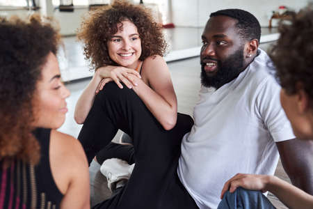 Smiling Afro American guy sitting with friends in dance classの写真素材