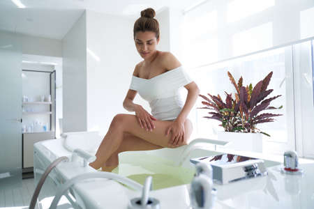 Calm beautiful lady getting into the water in spa salonの写真素材