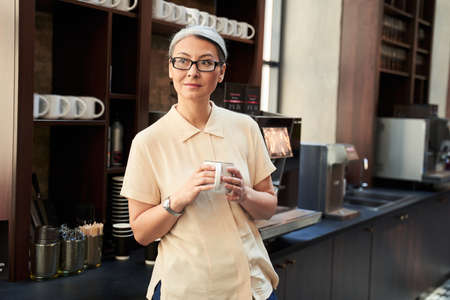 Calm beautiful woman enjoying her hot beverageの写真素材