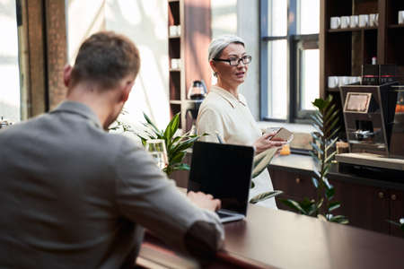 Cafe owner checking the working process and looking busyの写真素材