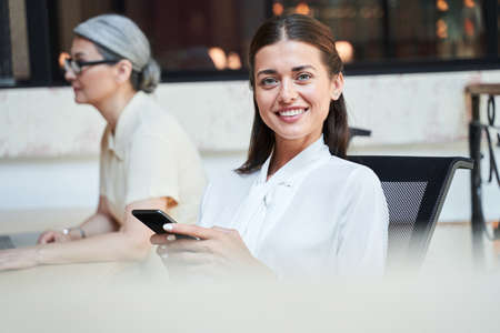 Excited young woman sitting in a chair with a phoneの写真素材