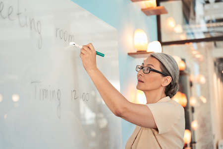 Seriously adult woman speaker writing message for new worker in the meeting room