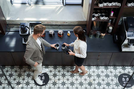 Cheerful business partner standing near the coffee machine