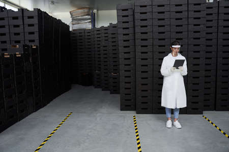 Focused warehouse employee standing among cardboard boxesの写真素材