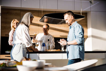 Smiling adult people enjoying wine at home