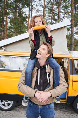 Girl eats corn while sitting on dads shouldersの写真素材