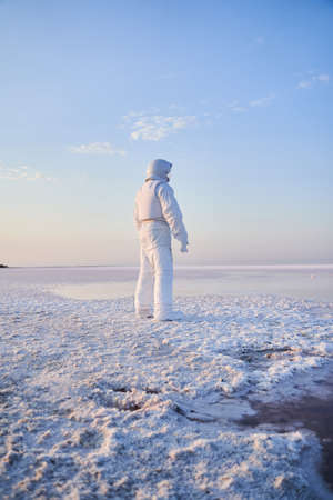 Spaceman rocket suit standing with back on salty lakeの写真素材