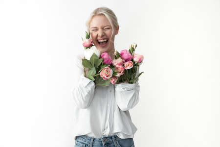 Happy young woman pressing her arms with flowers to her chest
