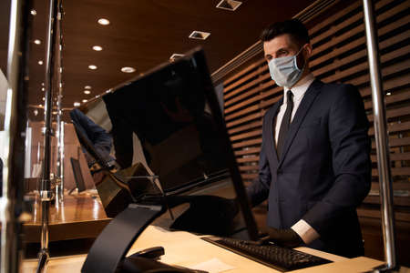 Concentrated receptionist using computer at his workplaceの写真素材