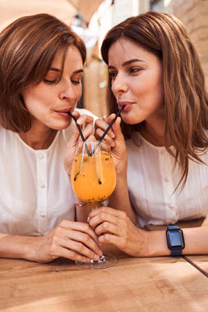 Girls drinking smoothie from one glassの写真素材