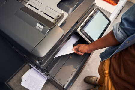 Man holding paper while using photocopy machine