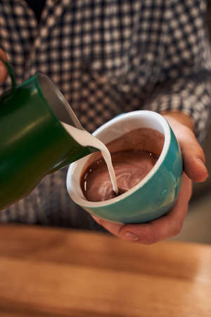 Mans hands pouring a milk into cacao