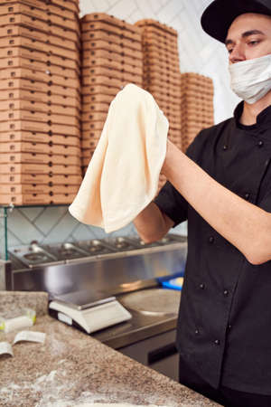 Pizzaiolo with prepearing dough for pizza