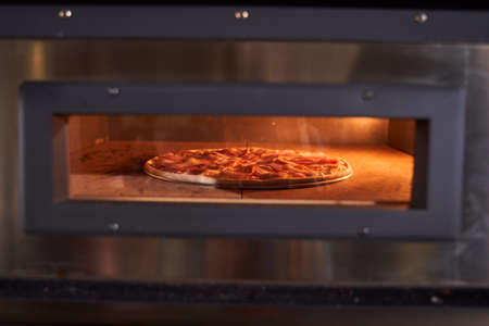 Baking pizza in electric ovenの写真素材