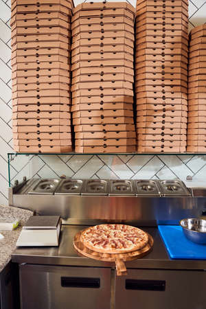 Pizza in kitchen amoung stacks of pizzas