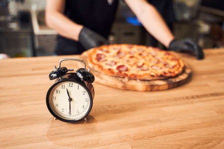 Close up alarm clock with pizza and backer