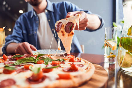 Cropped portrait of man with beard eating tasty pizza