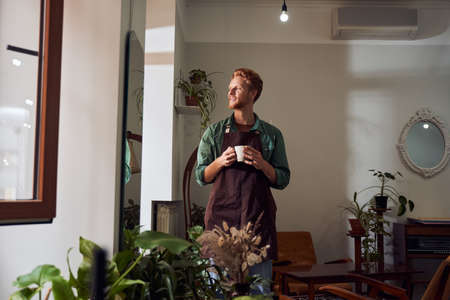 Florist in mask holding plants in pots