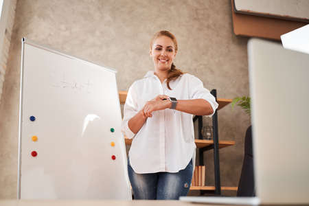 Mirthful lady pointing to her smart watch and smilingの写真素材