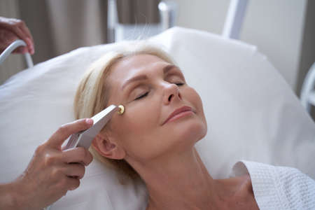 Beautiful mature female having cometological procedures in the beauty clinicの写真素材