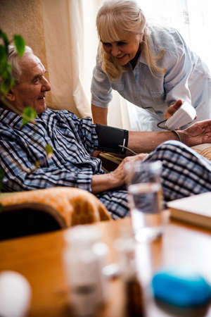 Woman in casual wear using tonometer to measure blood pressureの写真素材