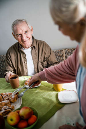 Woman is putting a pie to her husbandの写真素材
