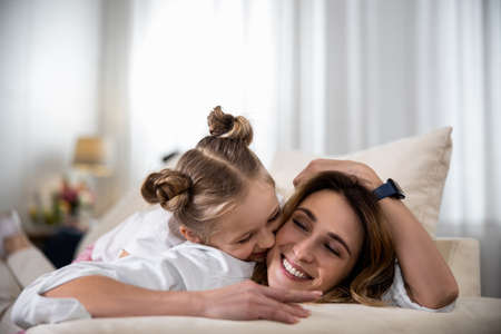 Daughter kissing her mother on the cheekの写真素材