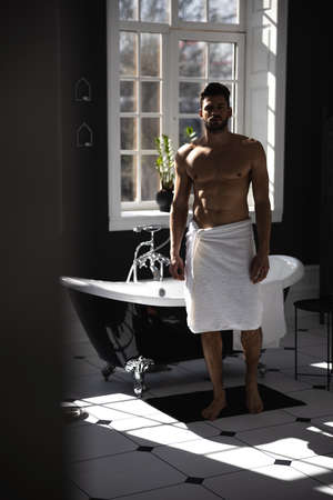 Portrait of man wrapped in towel in modern bathroom