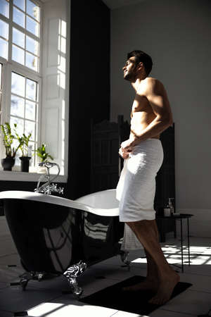 Cropped shot of man wrapped in towel in modern bathroomの写真素材