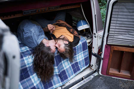 Couple kissing while laying at the trunkの写真素材