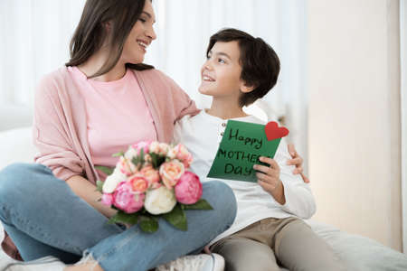 Boy with a greeting card looking at his mother
