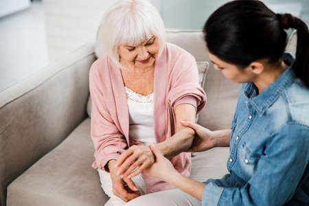 Family doctor holding arm of elderly woman