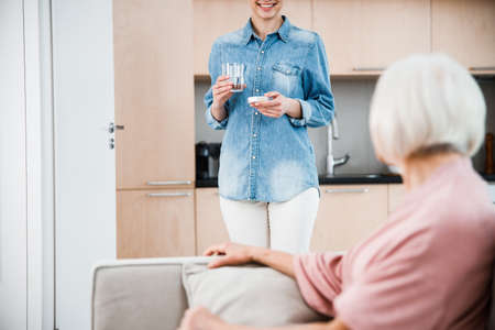 Cheerful granddaughter is holding pills for granddaughterの写真素材