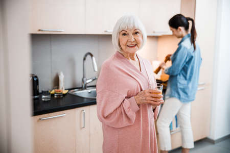Cheerful old woman holding glass of orange juice
