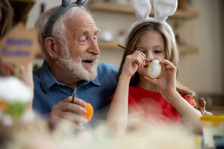 Happy elderly man preparing for Easter with granddaughter stock photo