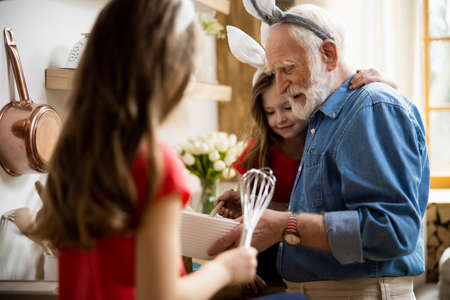 Caring girls helping grandpa with cooking stock photo