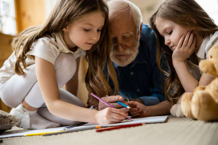 Calm kids drawing at home with grandpa stock photo