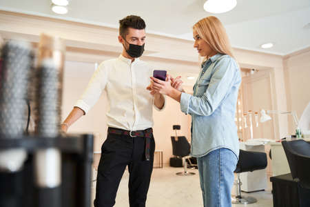 Woman showing a smartphone screen to her barber