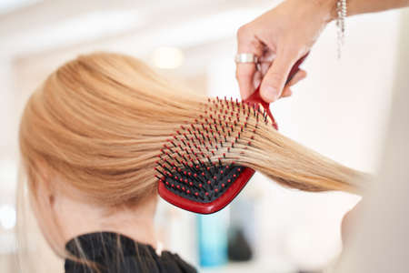 Hairdresser brushing long blonde hairの写真素材