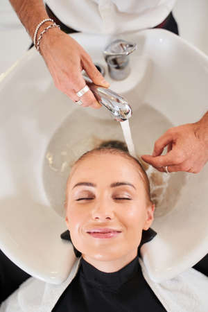 Hairstylist washing hair at the washbasin