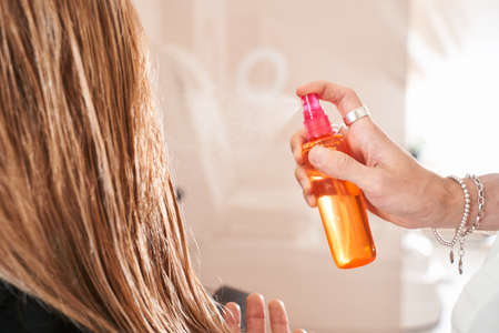 Hairdresser using a hair spray for styling the hair